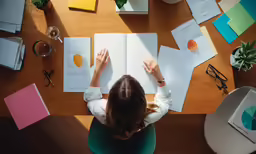 a woman sitting at a desk in front of an open book