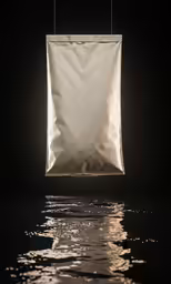 a white cloth hanging over water reflecting on dark background