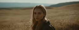 woman staring into camera in a grassy field