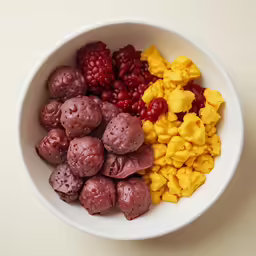 a bowl with some berries, mangos and grapes