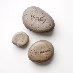 three pebbles with name written on them sitting next to each other