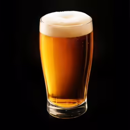a glass of beer sitting in the dark
