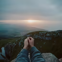someone is standing on a rocky mountain overlooking the valley