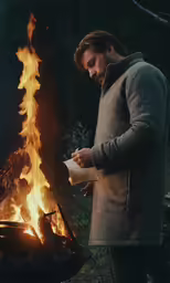 the man in the jacket is standing over a fire