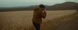 a man wearing a hoodie is standing on a trail