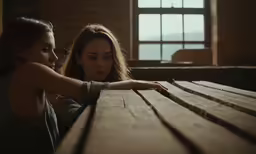 two women at a table are touching their hands