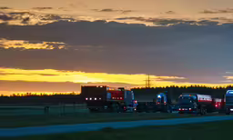 semi trucks lined up against each other parked near each other on a road,a couple of trucks that are next to each other