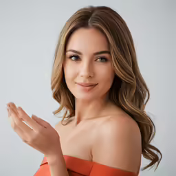 a woman in an orange top smiling with one hand outstretched up