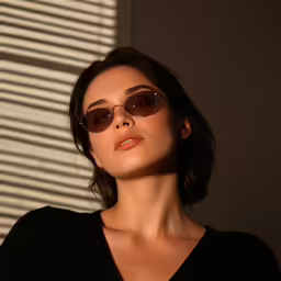 a woman with sunglasses and a black top stands near the window