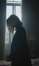 woman standing in a dark room with windows