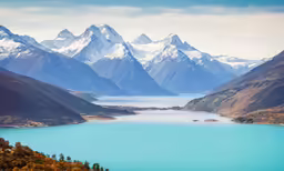a blue lake with many snow covered mountains in the background