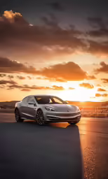 a car sits in the middle of an asphalt road as the sun sets