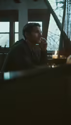 a young man sitting next to a table filled with candles