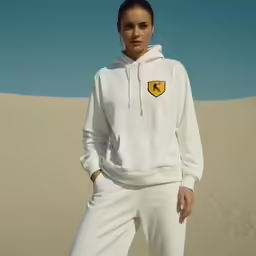 a woman wearing a white sweatshirt with a yellow badge