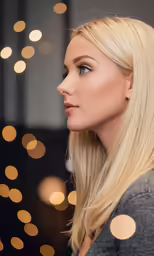 blonde woman looking at christmas lights in the background