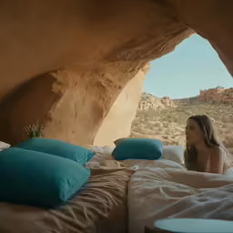 a beautiful young woman sitting on top of a bed in a bedroom