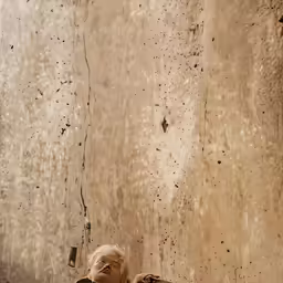 a man lying on the ground in front of a dirty wall