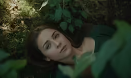 a woman is laying on the ground next to some plants