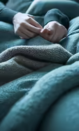 a person laying on a bed covered in a blanket