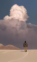 the person is walking across the desert looking at a cloud