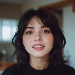 a woman with long black hair and a black shirt is smiling