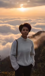 a woman in a sweater stands on top of the mountain above the clouds