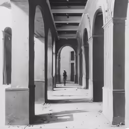 a person standing alone near a set of columns in a building