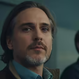 a close up of a person with a goatee and a serious look on his face