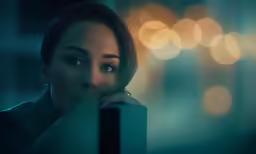 a woman posing for a portrait with city lights in the background