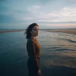 a woman stands alone in the water looking at the camera