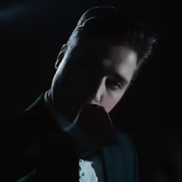 the young man is dressed in a tuxedo and looking intently away