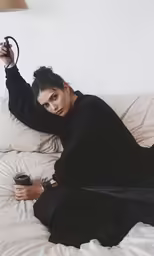 a woman lying on her side holding an object in one hand