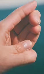 the small hand is holding something that has some nail in it