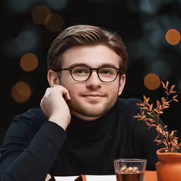 a man in a black sweater and glasses smiling at the camera