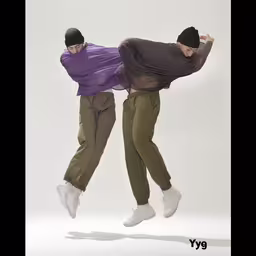 two people on their legs and a hat are seen in the air,the two men are jumping in the air with one leg lifted