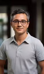 a man in glasses poses for a photo