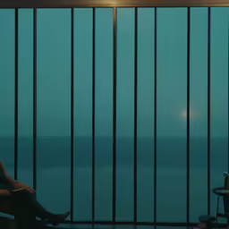 a man sitting in front of a window next to a chair and television
