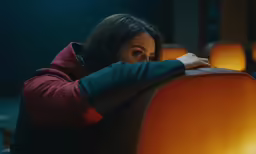 a woman in a black and red sweatshirt sitting in an orange chair