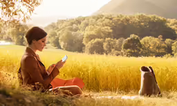 a woman is sitting in the grass holding a cell phone