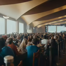 a large room full of people sitting in front of tables