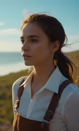 a woman standing on the beach with her hair in a ponytail