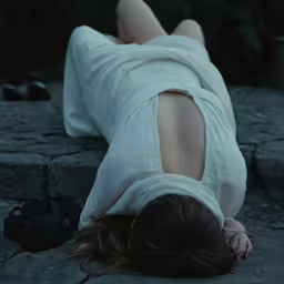a woman wearing a white shirt lying on the ground
