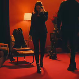 woman in black suit standing near a lamp and chair