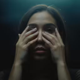 a woman in black with hands on her face