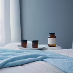 a white bed with two jars of liquid sitting on the bed