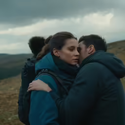 a couple embracing in a field under grey skies