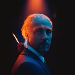 a man with blond hair and a long beard wearing a dark suit
