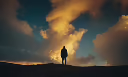 a person stands on top of a hill at sunset