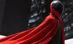 a person dressed in a red cape and black suit,