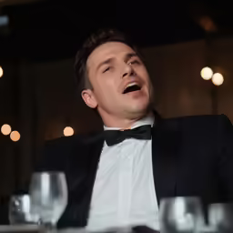 the man is dressed in a tuxedo and singing